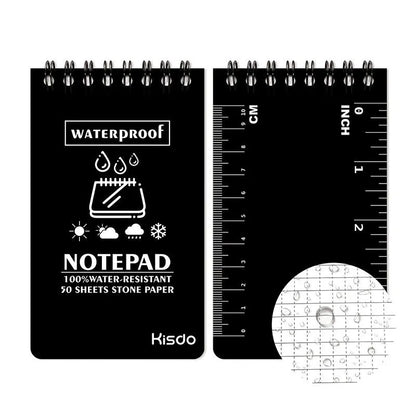 Spiral-bound waterproof notepad in camouflage colour, open on a desk with a pen, showing stone paper pages.