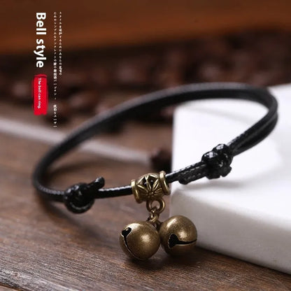 A small dog's nylon rope halter collar with a brass bell and buckle on a black background.
