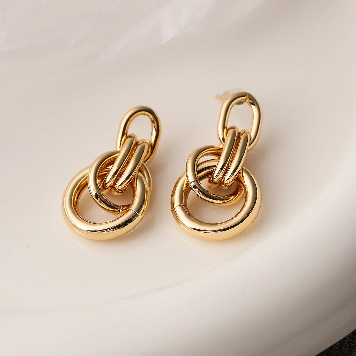 Geometric gold-coloured copper earrings with irregular asymmetric design