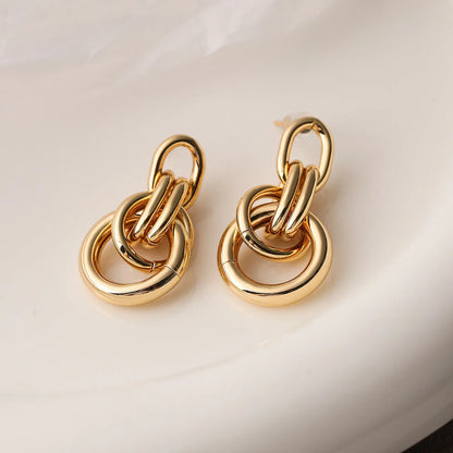 Geometric gold-coloured copper earrings with irregular asymmetric design