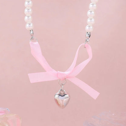 Love heart and bow tie clavicle chain necklace with pearl inlay, shown in White K Love 028 and White K Bow 026 options.