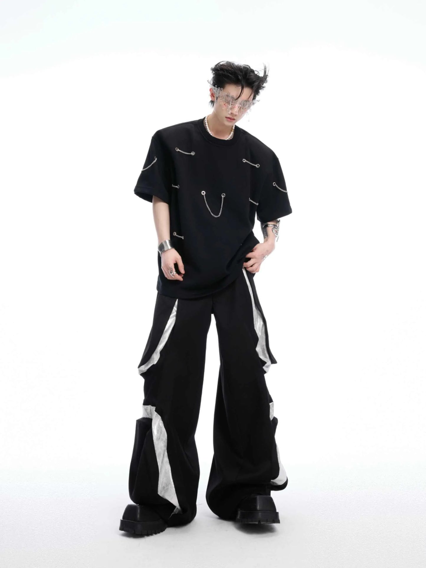 Black padded shoulder T-shirt with metal chain detail on model, showing short sleeves and round neck.