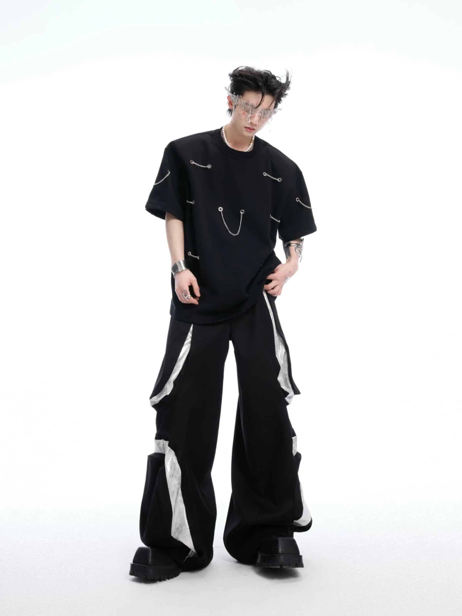 Black padded shoulder T-shirt with metal chain detail on model, showing short sleeves and round neck.