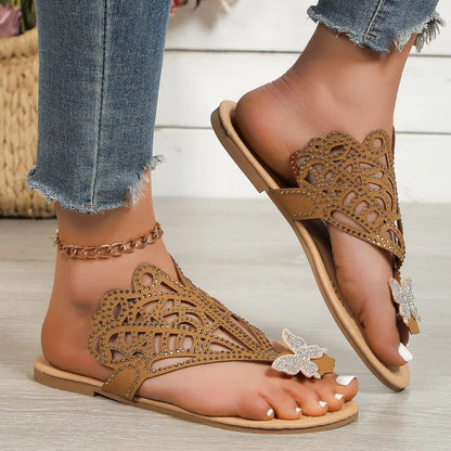 Women's black slip-on flip-toe sandals with rhinestone accents and hollow flat-heeled design on a light background