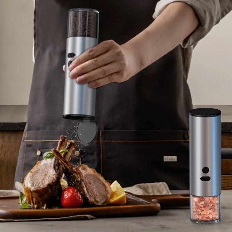 White electric salt and pepper grinder with stainless steel top and clear glass jar on a kitchen counter.