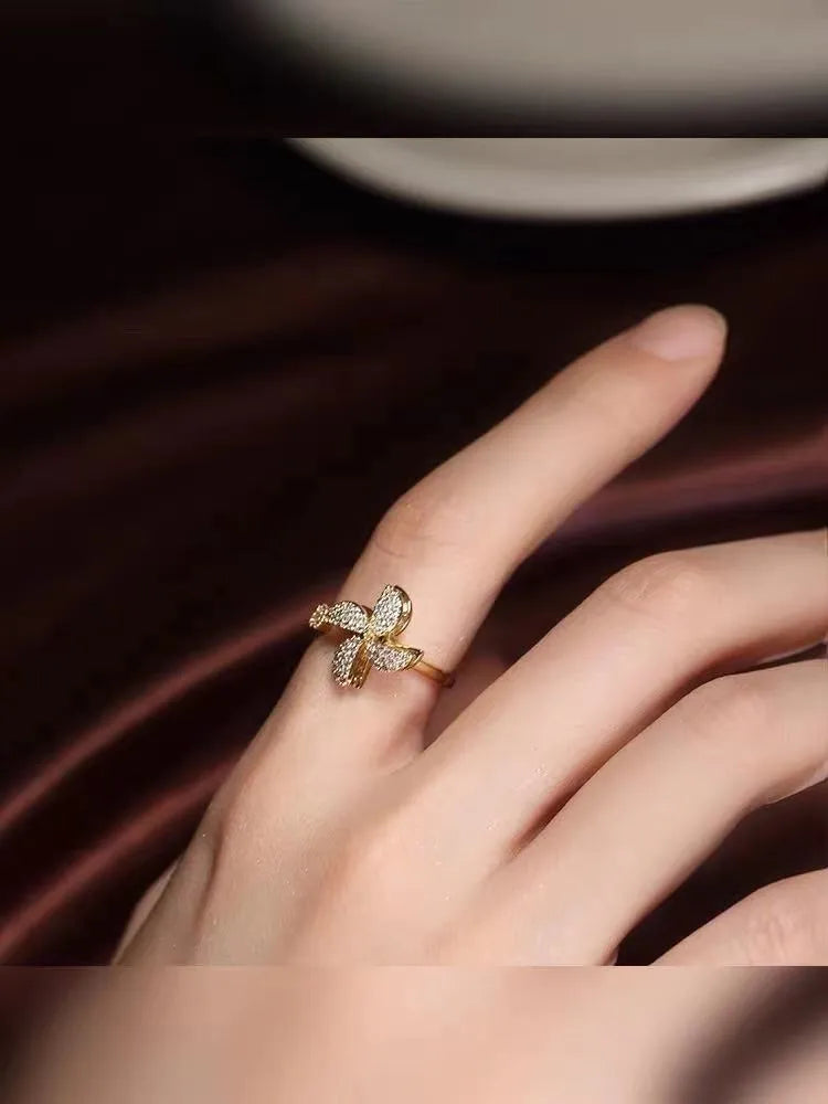 Gold rotating ring with a spinning geometric windmill design on a person's finger