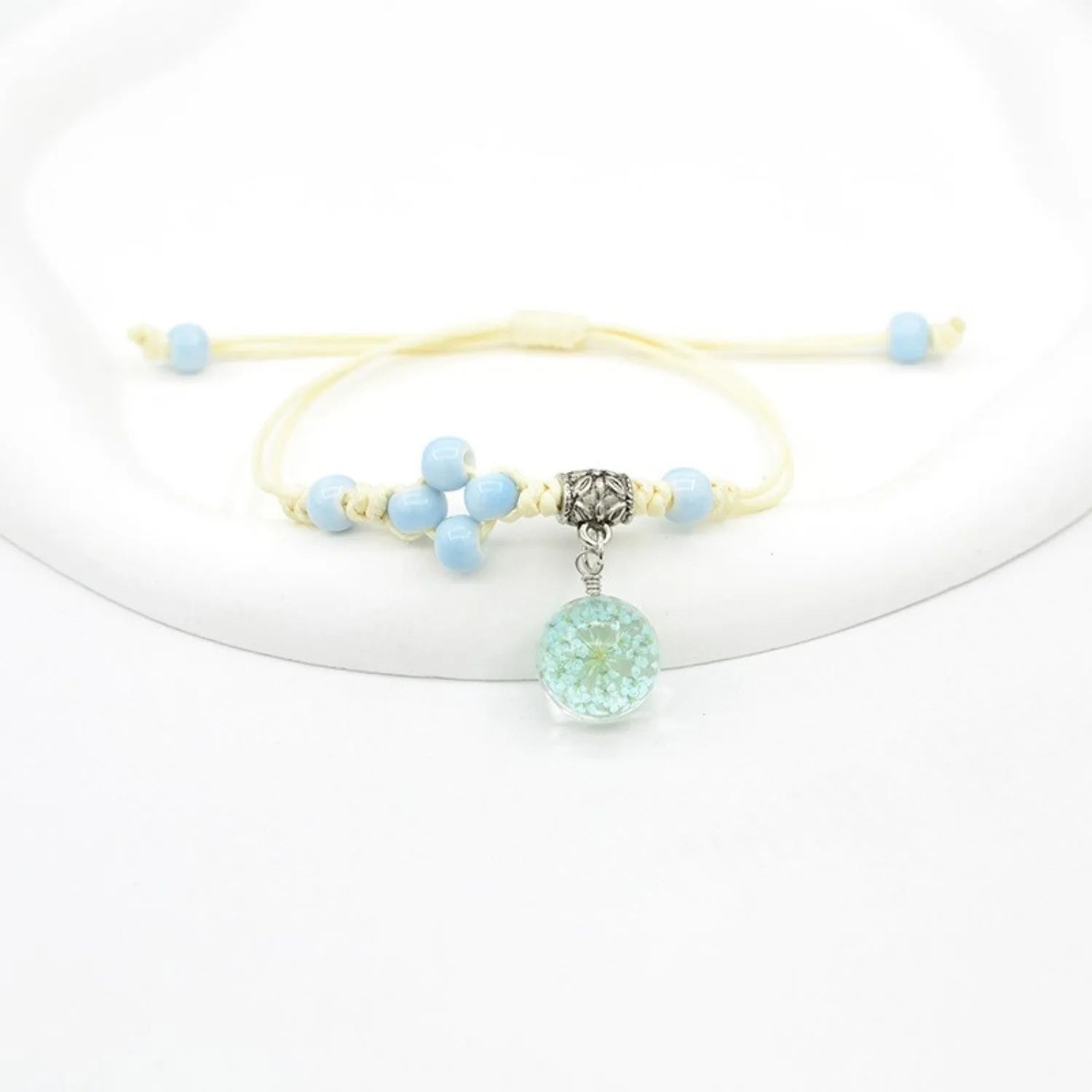 Hand-woven glass bracelet with large 1.4 cm beads containing real dried flowers, shown in blue.