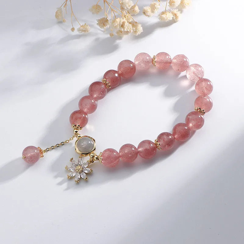 A Mori style crystal bracelet made with natural pink strawberry quartz stones and delicate electroplated floral charms.