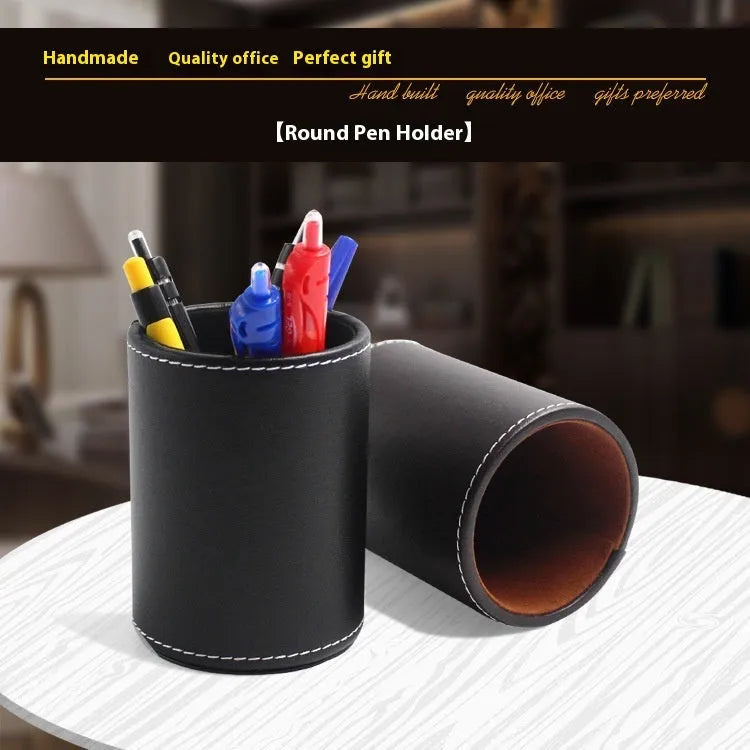 Round black leather pen container measuring 8.0cm diameter by 10.8cm height on wooden desk