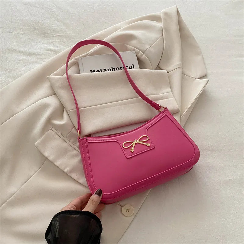Western style shoulder bag with bow detail in rose pink colour, showing horizontal square shape and single strap.