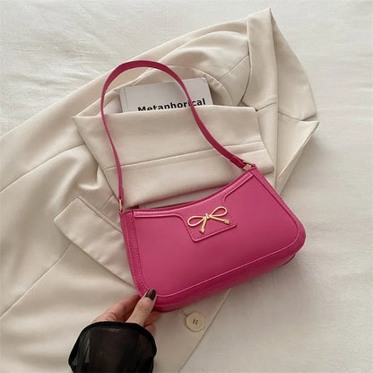 Western style shoulder bag with bow detail in rose pink colour, showing horizontal square shape and single strap.