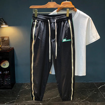 Man wearing black cotton harem-style sport trousers with an elasticated mid-waist.