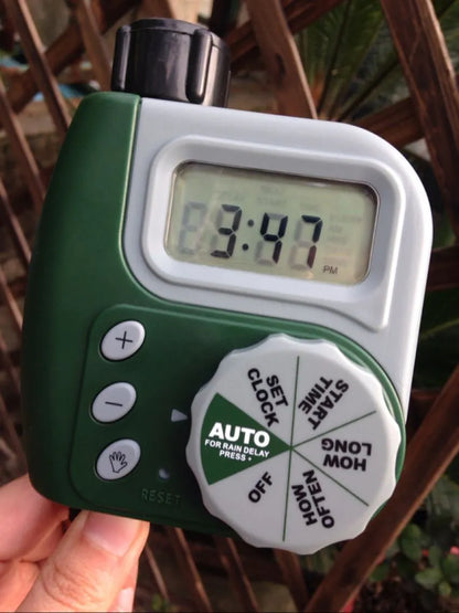 Green digital garden hose timer with LCD screen and dual hose outlets.