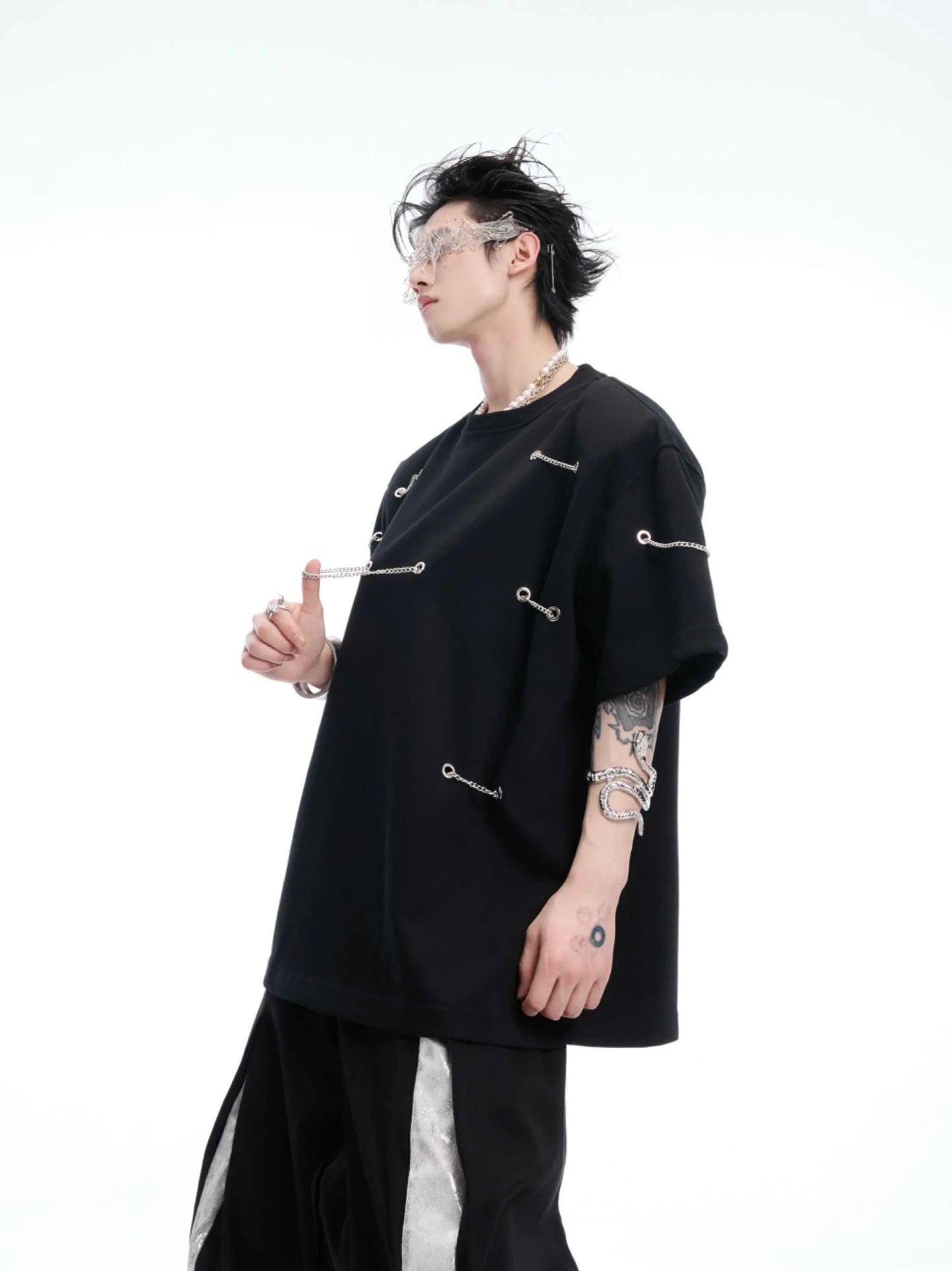 Black padded shoulder T-shirt with metal chain detail on model, showing short sleeves and round neck.