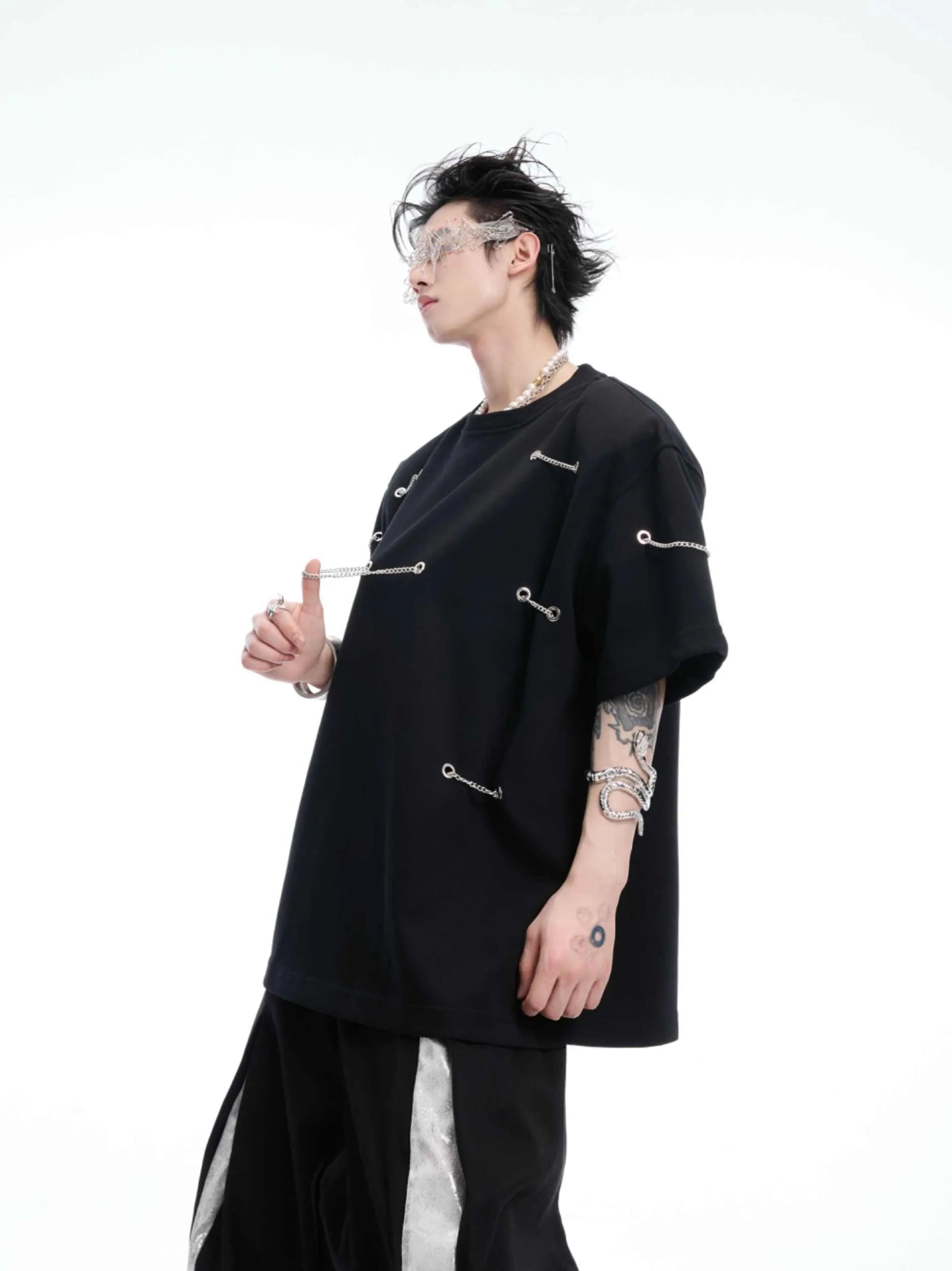 Black padded shoulder T-shirt with metal chain detail on model, showing short sleeves and round neck.