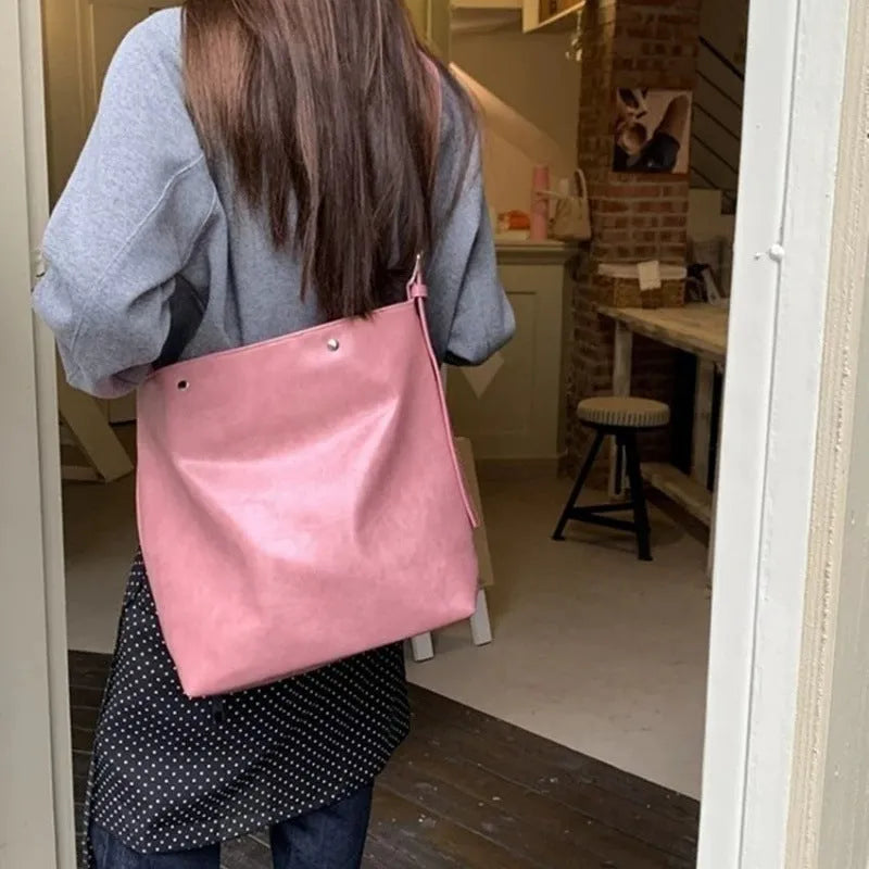 Pink corduroy one-shoulder bag showing its textured fabric and single strap.