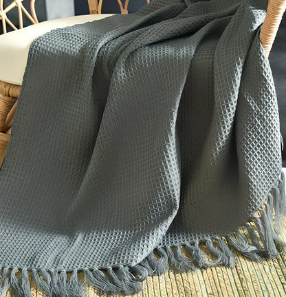 130x150cm knitted acrylic blanket with 10cm fringe detailing in beige colour draped over sofa
