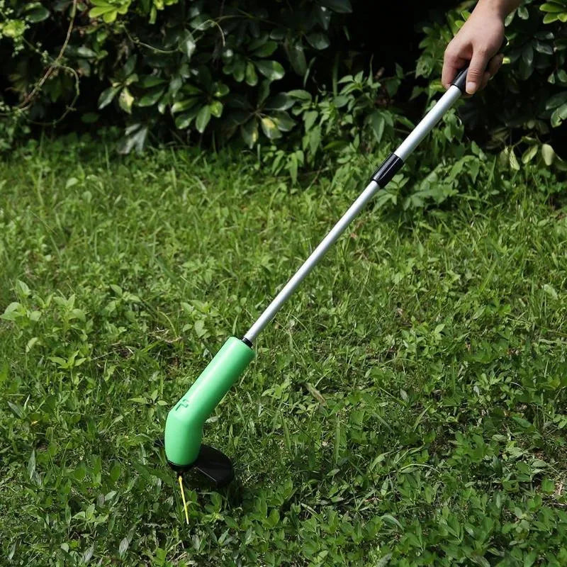 Cordless handheld lawn trimmer with green housing, extension pole, debris shield, and pack of zip ties on a garden lawn.