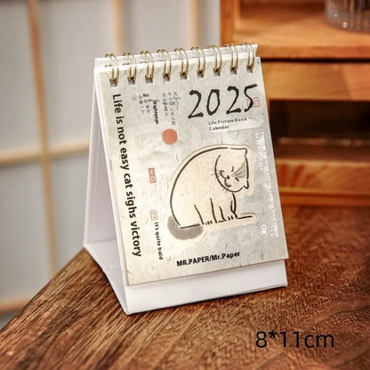 2025 mini desk calendar showing one of four designs: Coffee Time, Awake Time, Corner Perching, or Afternoon Lazy.