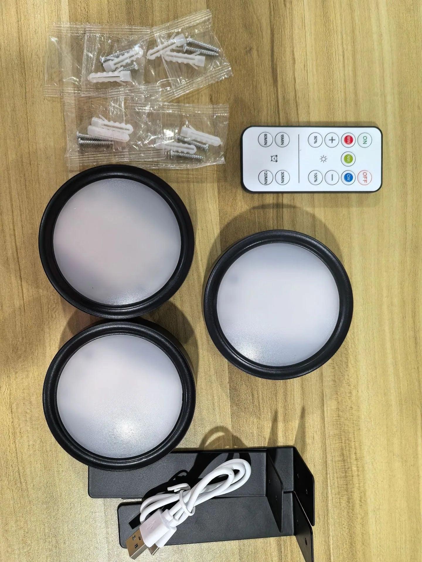 Black magnetic LED painting lamp with remote control on a white wall.