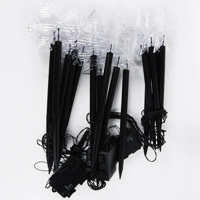 Snowflake-shaped garden lights with warm, soft glow illuminating an outdoor garden or patio area