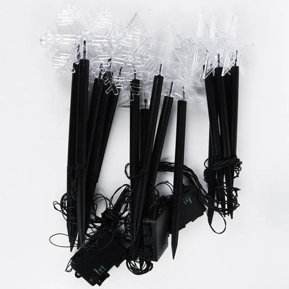 Snowflake-shaped garden lights with warm, soft glow illuminating an outdoor garden or patio area