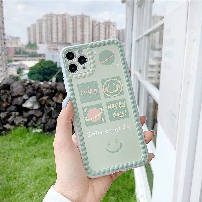 Green TPU iPhone case with geometric smiley face and polka dot frame design on a smartphone