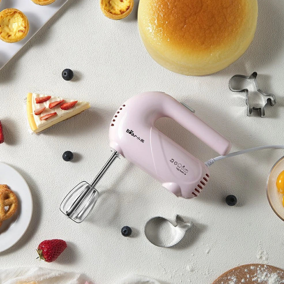 Pink electric hand whisk with stainless steel attachments for whipping eggs and cream