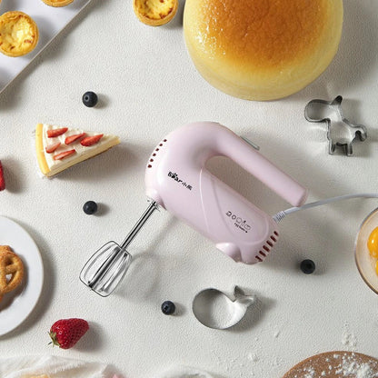 Pink electric hand whisk with stainless steel attachments for whipping eggs and cream