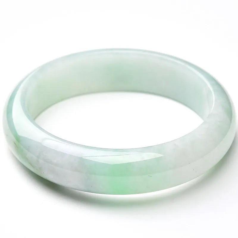 Light green solid jade bracelet on a wrist, showing its simple loop design and natural stone colour.
