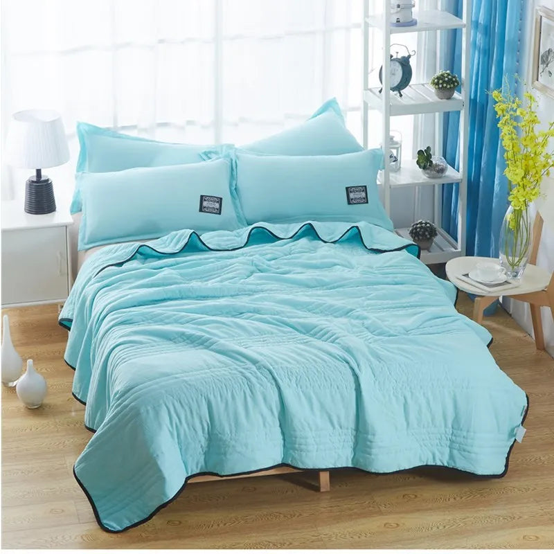 Lightweight plain coloured polyester summer quilt on a bed