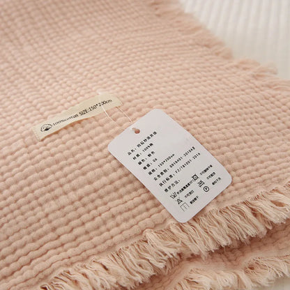Four-layer gauze tassel blanket in cotton, showing tassel edges and textured fabric, available in multiple colours and sizes