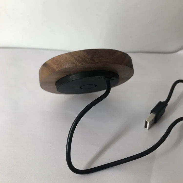 Round wireless charging unit for recessed installation in desks and tables, shown next to a smartphone.