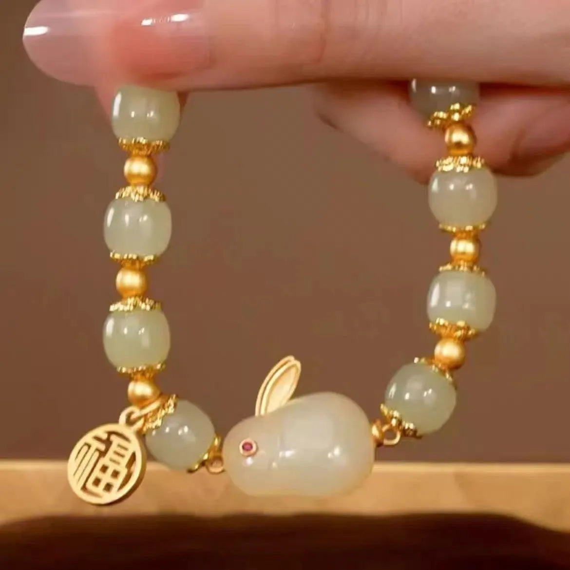 Green jade hare charm fu character bracelet with lily detail on black adjustable cord.