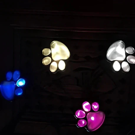 Four black paw-shaped solar garden lights with connecting wire and central solar panel for automatic outdoor illumination