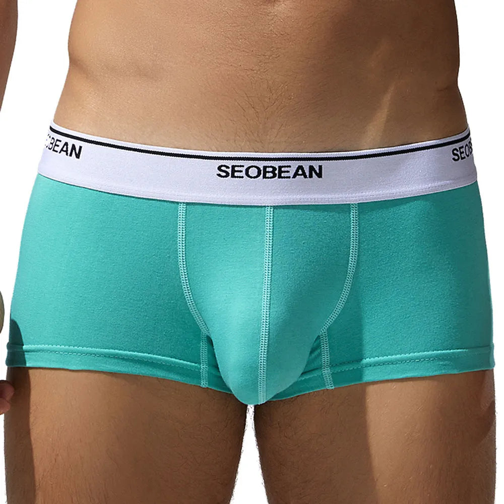 Men's solid colour cotton low waist boxers in white, blue grey, cyan, and black on a size label.