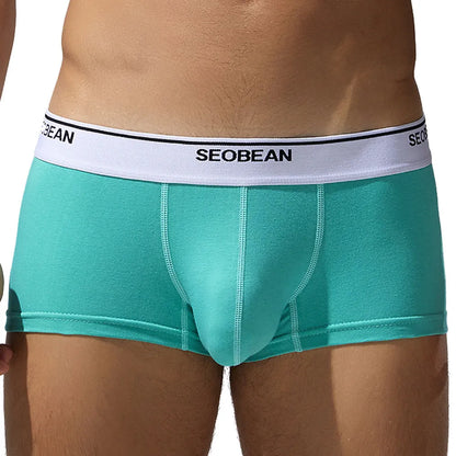 Men's solid colour cotton low waist boxers in white, blue grey, cyan, and black on a size label.