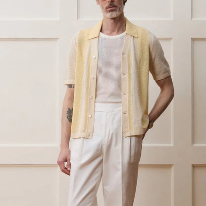 Yellow asymmetric short-sleeved polo shirt with hollow-out design on a hanger.