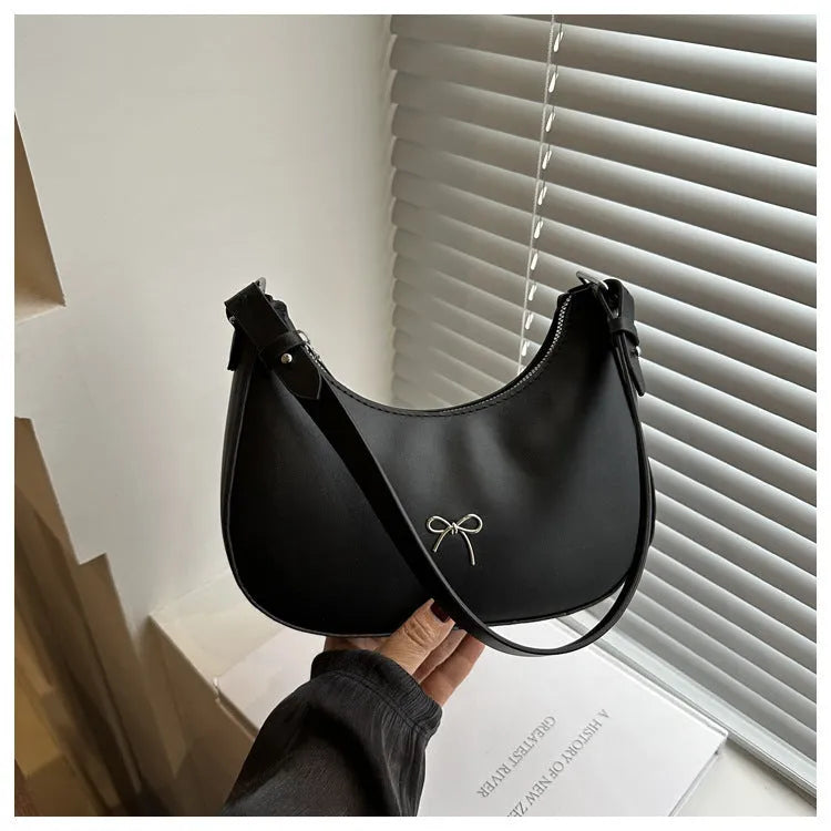 Women's silver dumpling-shaped PU crossbody bag showing front sandwich pocket and single shoulder strap.
