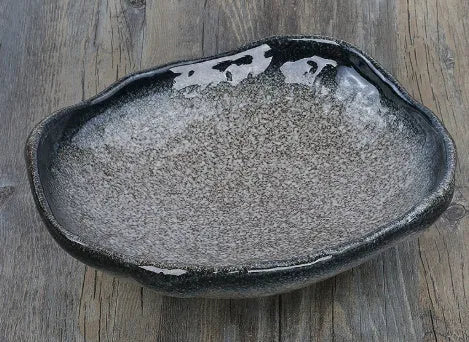 Japanese style irregular shaped ceramic sashimi bowl with floral decoration on table.