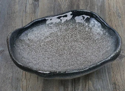 Japanese style irregular shaped ceramic sashimi bowl with floral decoration on table.