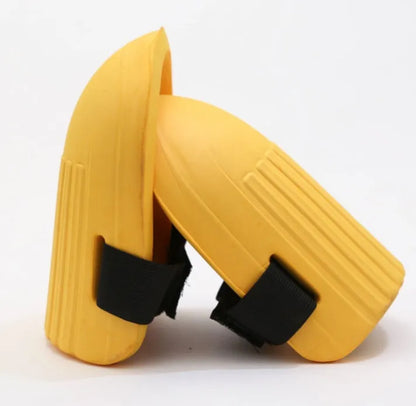 A pair of rectangular EVA foam knee pads in army green colour, placed on a garden soil background.