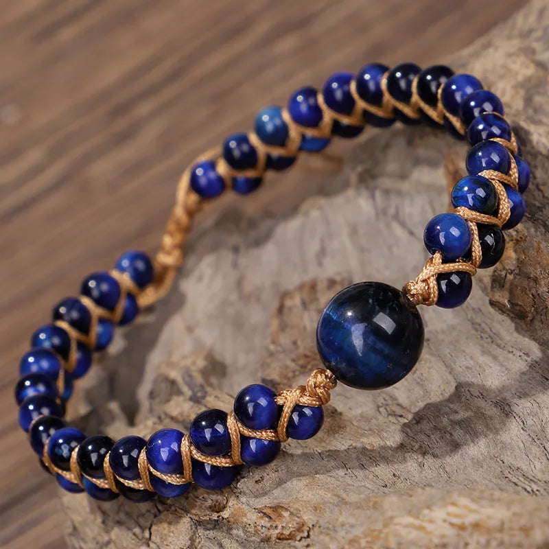 Handmade geometric pull bracelet woven from blue tigereye stone beads on a wrist.