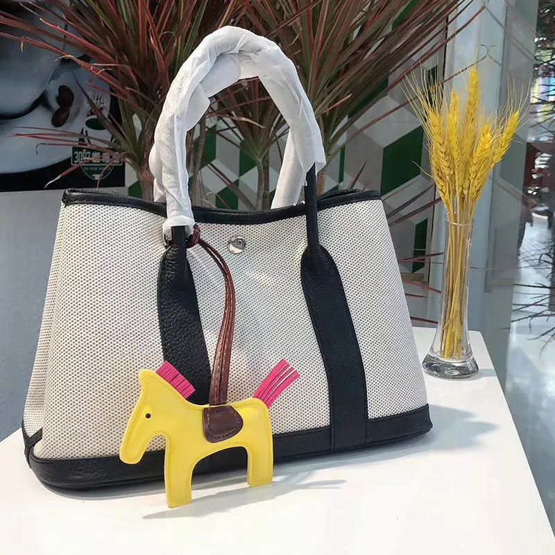 Genuine leather and canvas women's tote bucket bag in black, shown with a soft carry handle.
