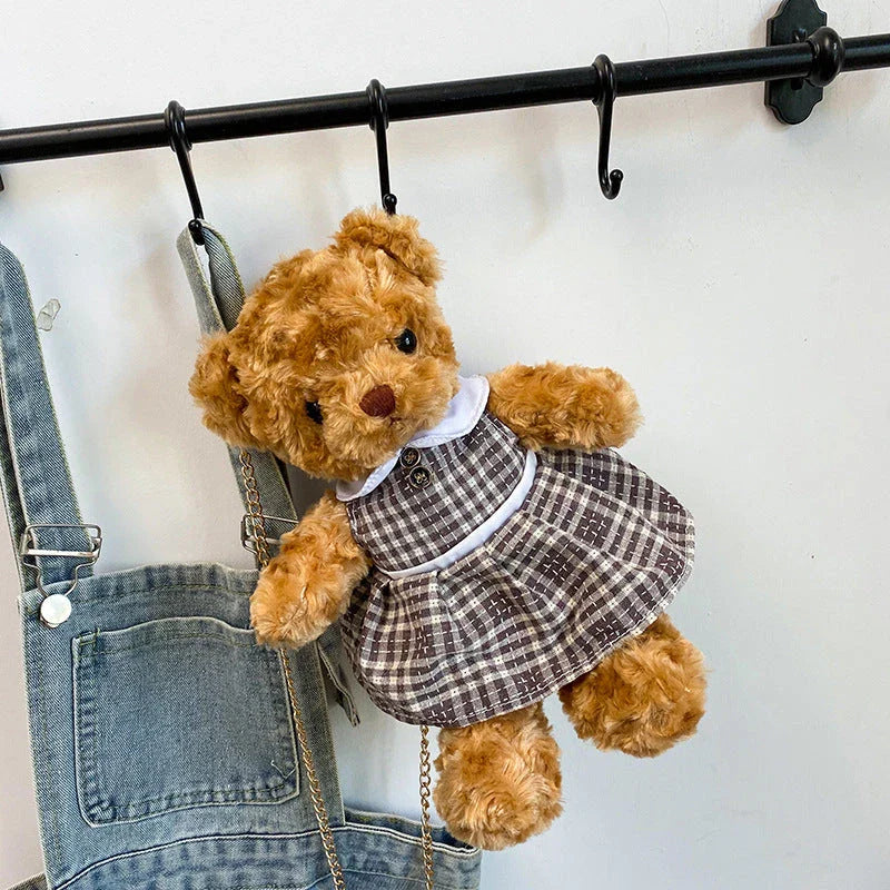 A plush teddy bear crossbody messenger bag with an adjustable shoulder strap and a zippered interior pocket for convenient storage.