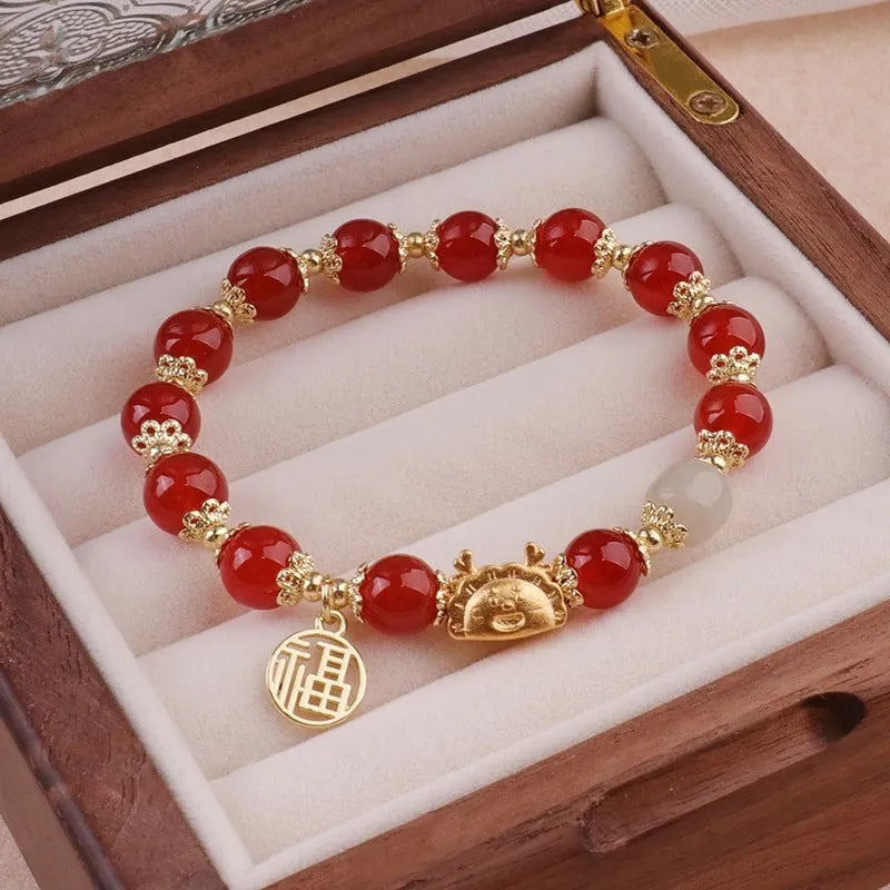 A women's glass glazed bracelet with floral and zodiac animal charms in red, pink, and white pearl beads.