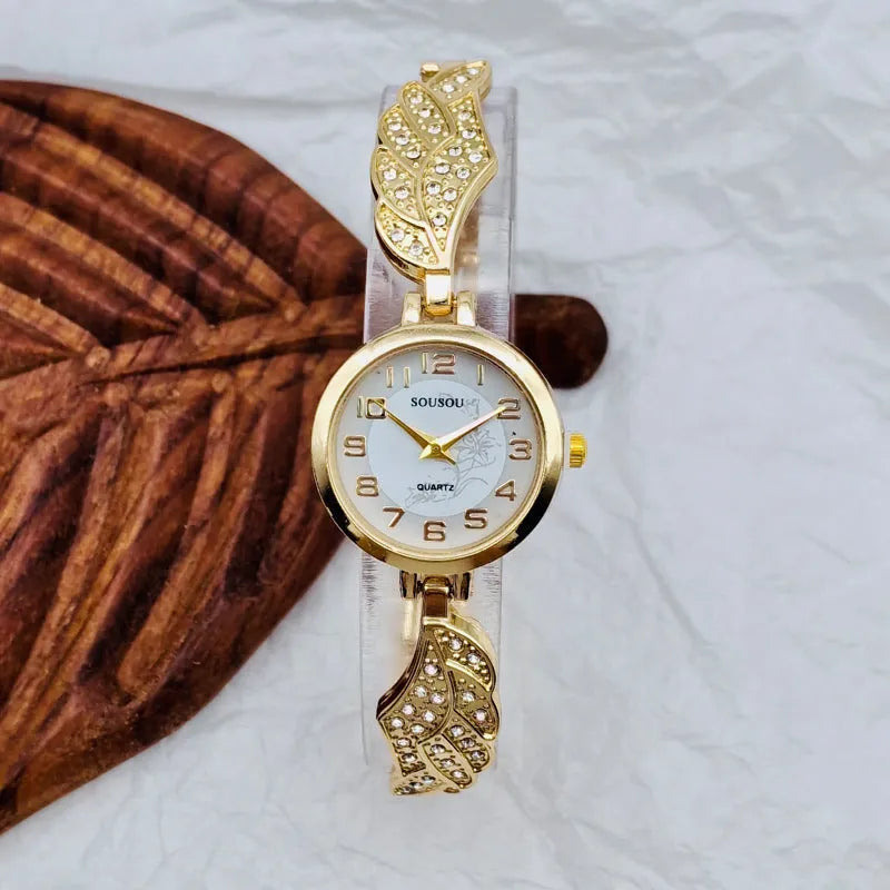 Round stainless steel women's watch on wrist showing gold surface colour and vachette clasp buckle.