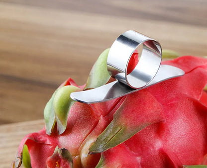 Silver stainless steel citrus fruit peeler with a ring handle on a wooden surface.