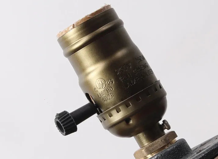 Compact wooden and iron water pipe table lamp on a table.