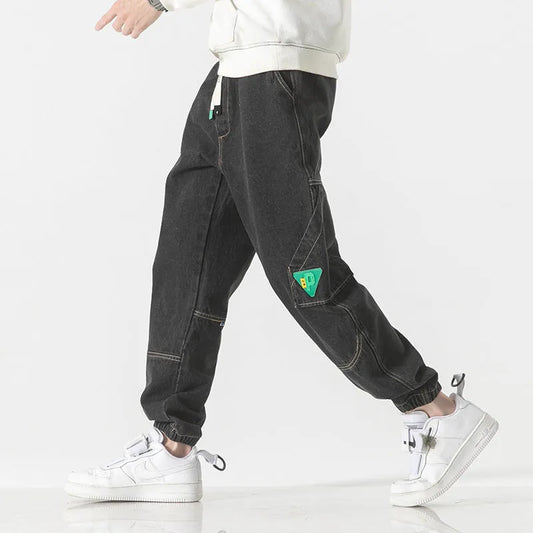 Men's loose-fit tapered cotton trousers in black showing mid-waist design and tapered leg opening